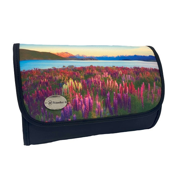A rectangular cosmetic bag with which secures with a Velcro strip across the top. The front of the bag displays a beautiful scene of pink and purple lupins, with New Zealand’s spectacular mountain ranges in the background, under a blue sky with wispy clouds. The front left corner hosts a silver badge with the AA Traveller logo. The back and sides are black, with a black Velcro strip and unfolds into 4 compartments.